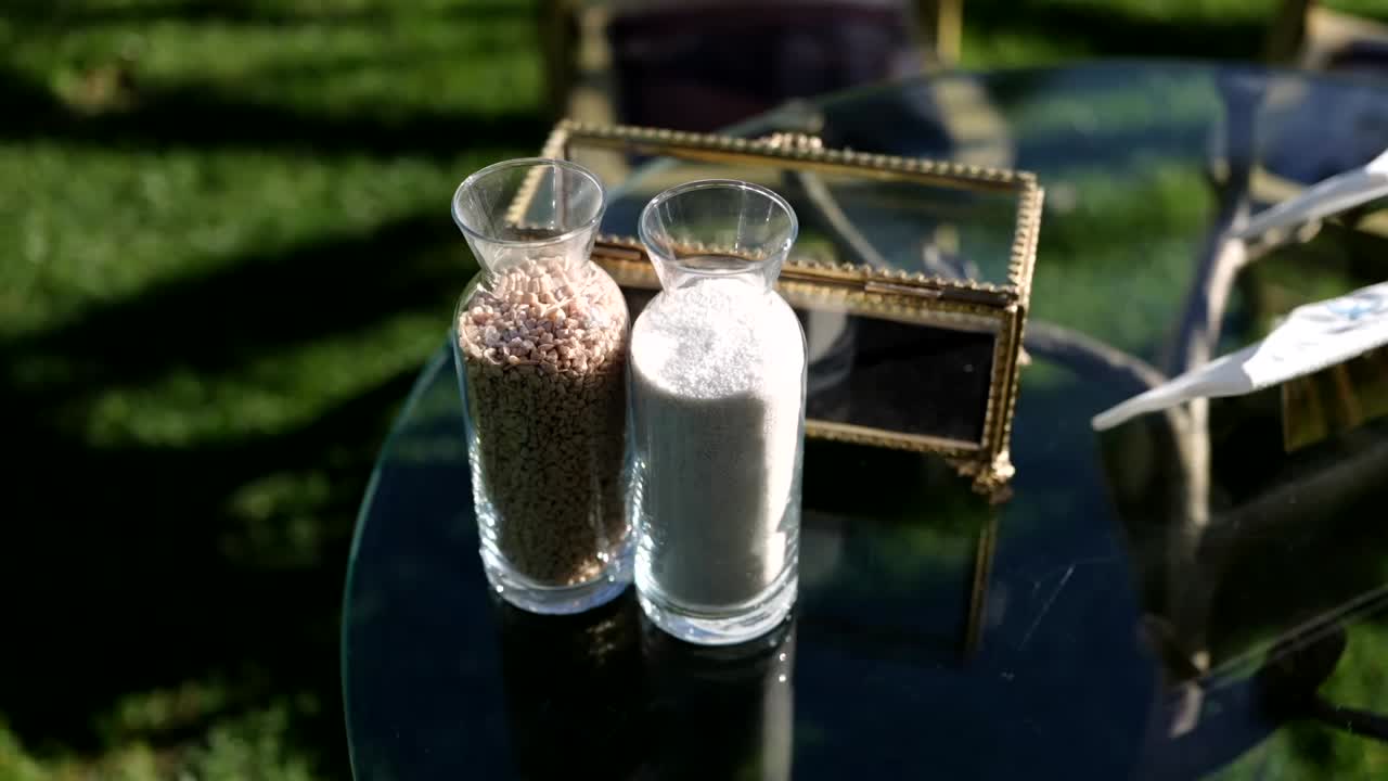 Two glass jars filled with white and brown grains on glass table