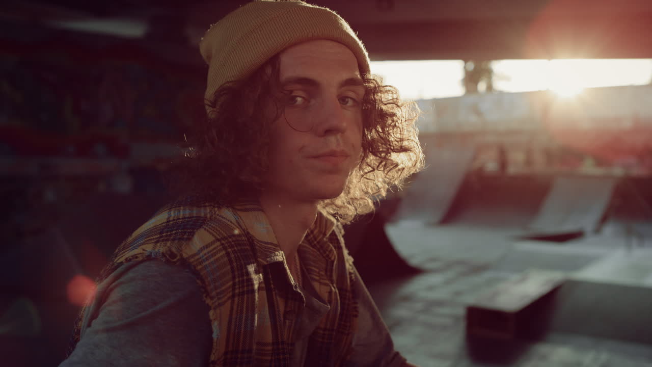 un adolescente relajado descansando después de entrenar en el parque de skate. un tipo mirando a la cámara.