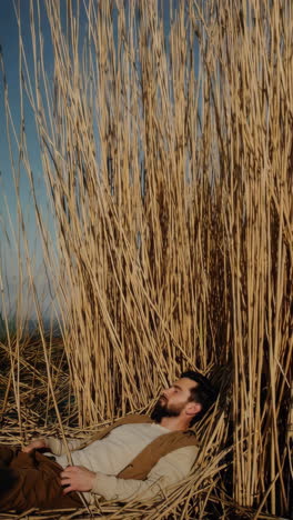 man resting among tall reeds
