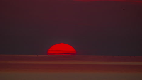 el sol naranja se sumerge más allá del horizonte del océano al atardecer - lapso de tiempo