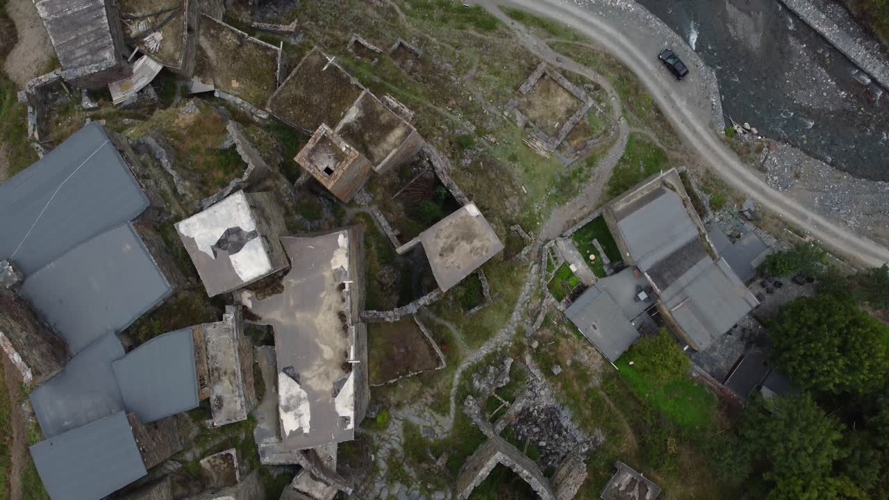 Top-down drone fly over ancient and historical Shatili's home rooftops clustered on mountain hillside, Khevsureti, Mtskheta-Mtianeti, Georgia