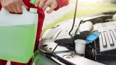 service worker man pours car fluid windscreen green cleaning washer glass summer or winter cleaner