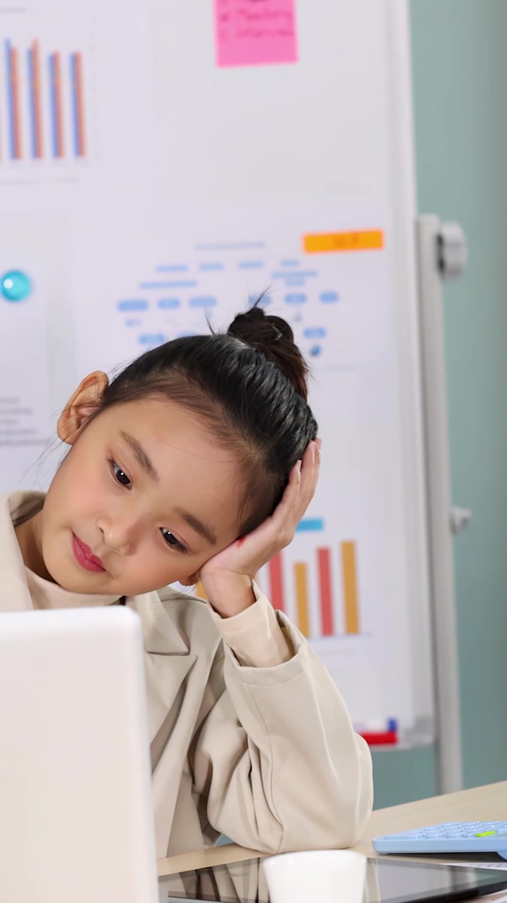 Giovane ragazza stanca in abiti da ufficio si appoggia sulla mano mentre lavora alla scrivania.