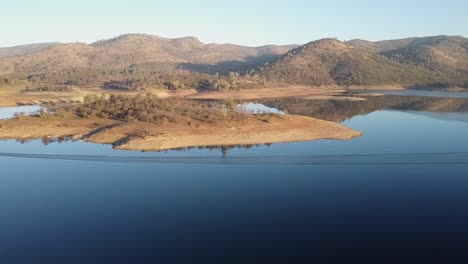 sweeping drone views showcase new hogan lake’s reflective waters, rolling hills, and scattered trees.
