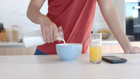 persona vierte leche en un tazón de cereales en un mostrador de la cocina