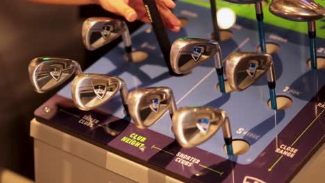 person choosing golf clubs from a display