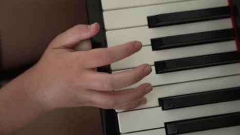 cerca por encima de las manos de la joven practicando la canción en el piano en casa