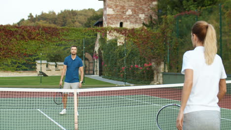 Glückliches-Paar,-Das-Zusammen-Tennis-Spielt-Und-Dann-An-Einem-Sommertag-Auf-Dem-Außenplatz-High-Five-Gibt