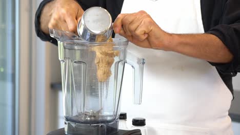 añadiendo mantequilla de almendra a la licuadora para hacer salsa para calabazas fideos zoodles añadiendo a la taza saludable vegano vegetariano estilo de vida dieta de desintoxicación