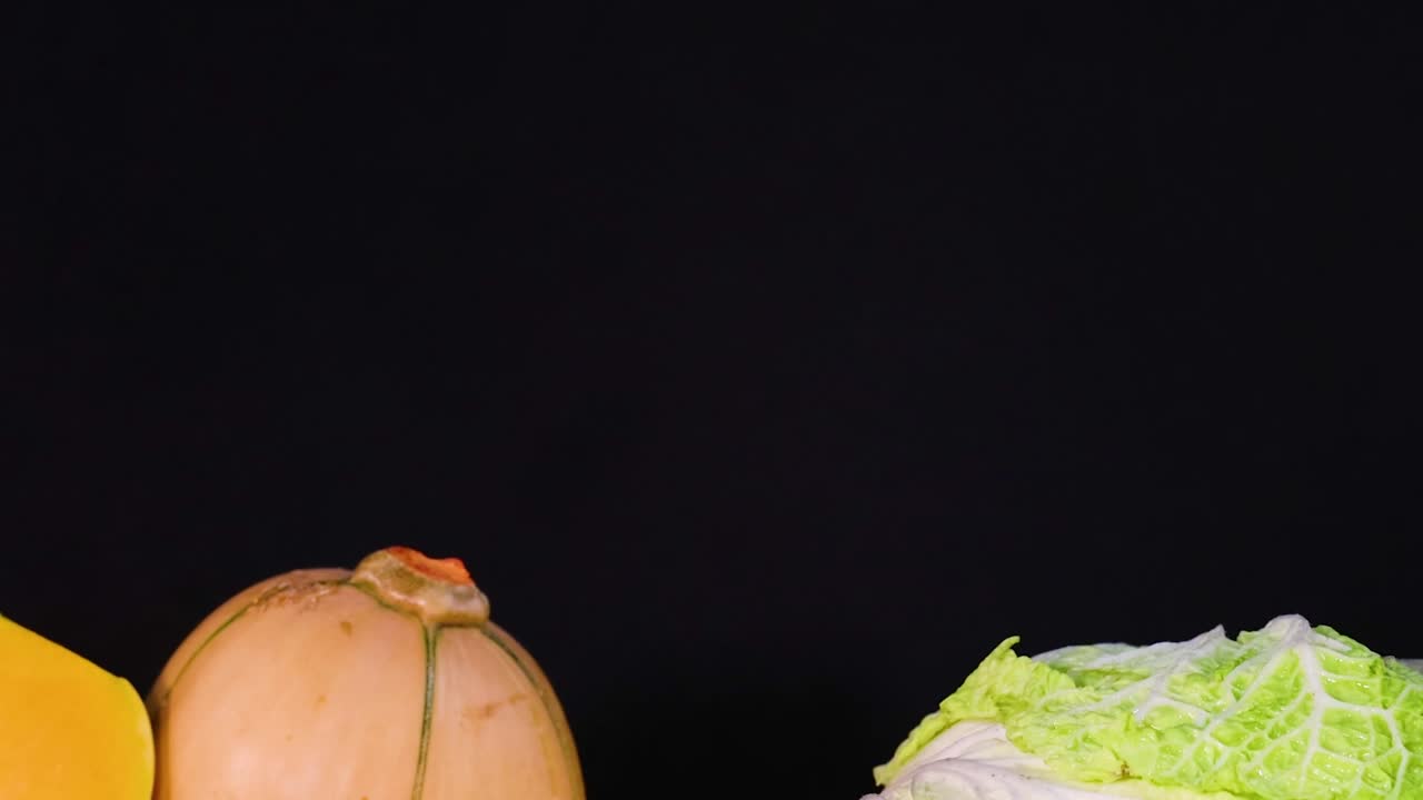 A colorful arrangement of squash, cauliflower, and assorted vegetables on a dark background.