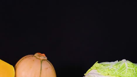 a colorful arrangement of squash, cauliflower, and assorted vegetables on a dark background.