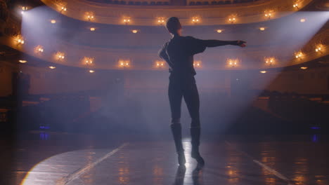 ballet dancer in training suit practices moves ballet dancer in training suit practices visual moves on theater stage and prepares to performance dancer on choreography rehearsal before show illuminated theatrical hall classical ballet art