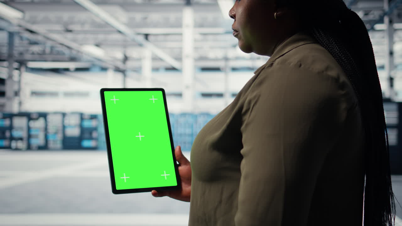 Software developer in data center using green screen tablet