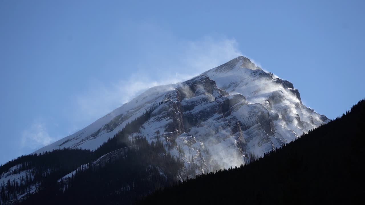 Rallentatore su una cima montuosa innevata con un cielo blu, ripresa con teleobiettivo.