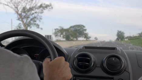 interior view inside vehicle over drivers shoulder in wet weather rain hitting windshield