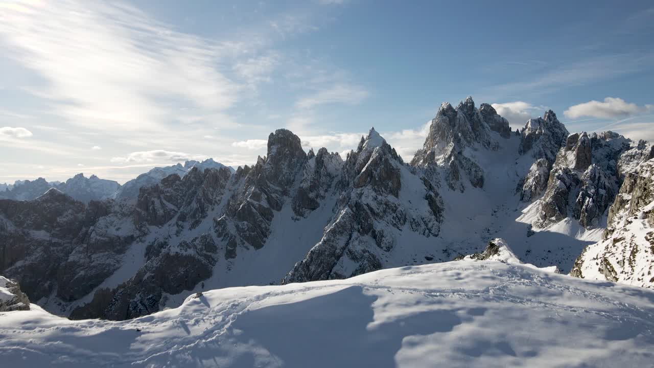 montañero camina sobre una cresta frente a los dolomitas durante el invierno