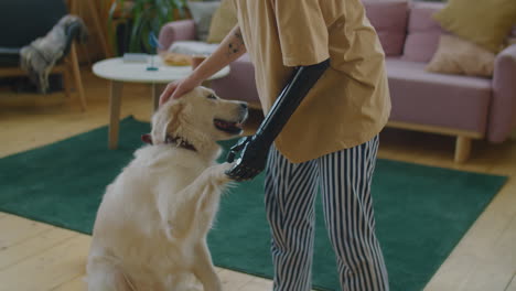 girl with prosthetic arm petting dog in living room