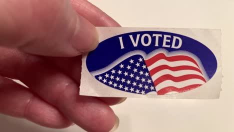 I-VOTED---Hand-holding-a-California-voting-sticker-over-white-background