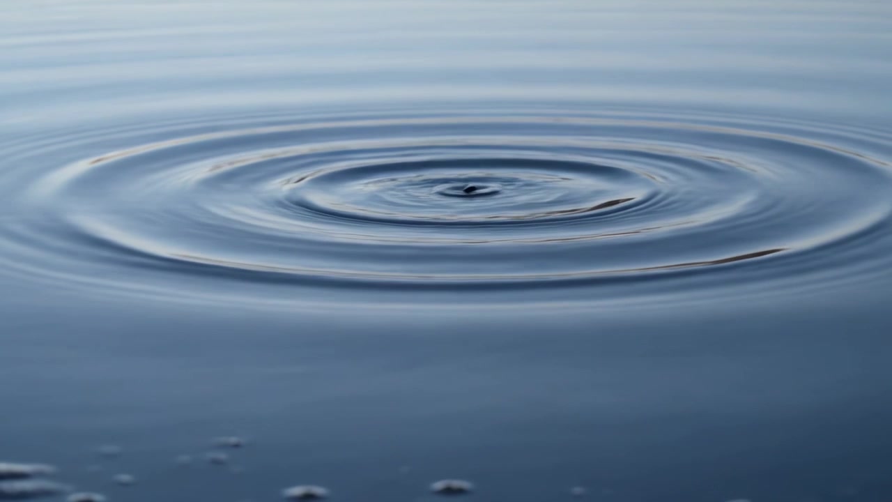 Creando increspature concentriche, uno schizzo centrale che rimbalza sullo stagno dopo l'impatto di una goccia, bolle
