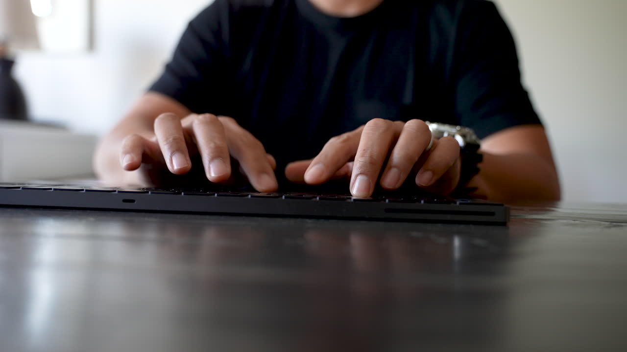 Typing male on black keyboard with watch