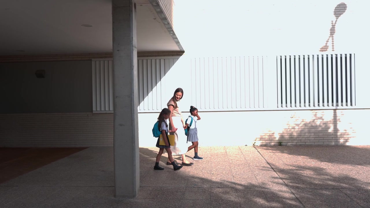 Mãe caminhando com suas duas filhas para a escola