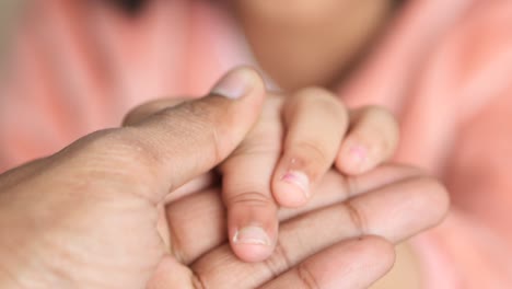 Father-holding-hand-of-baby-child,-close-up