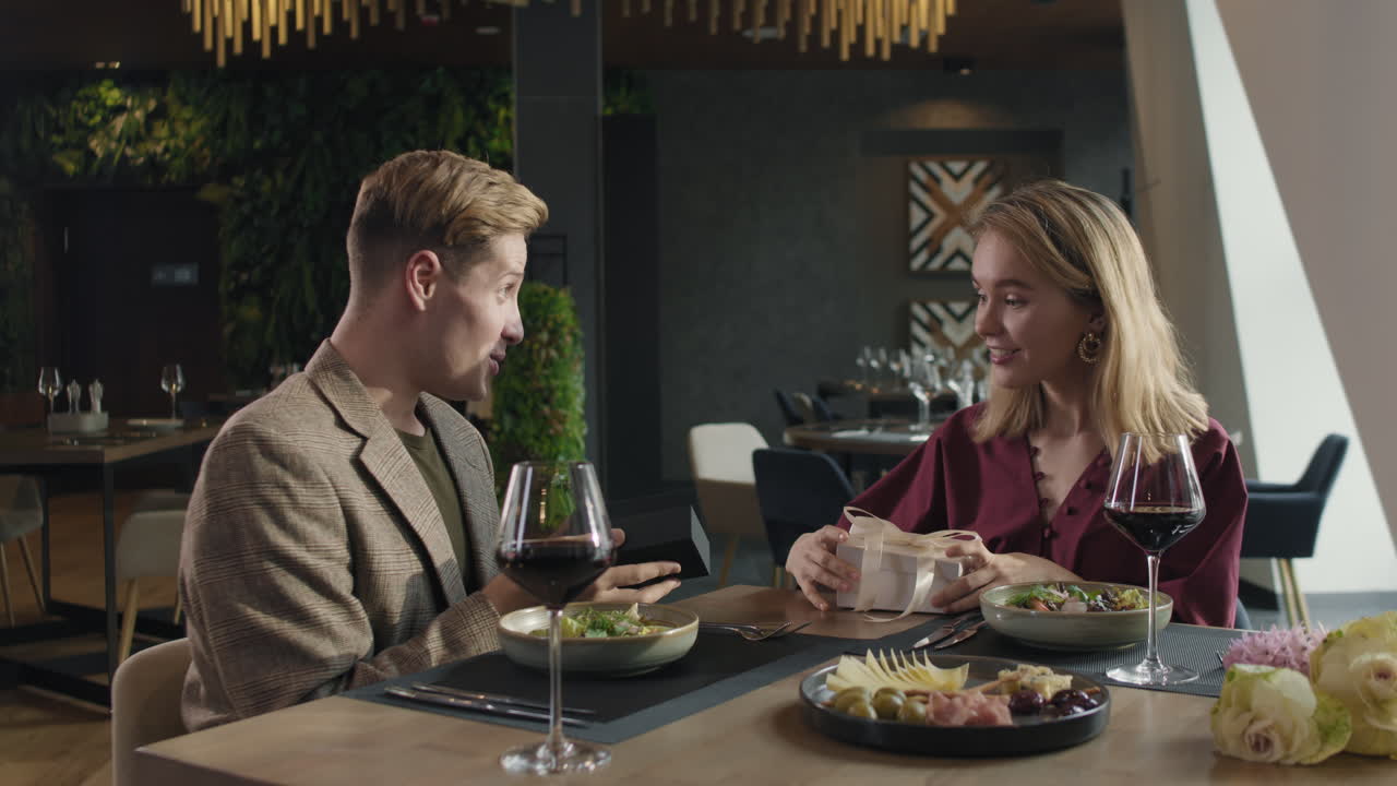 una pareja celebra una cena romántica con un regalo.