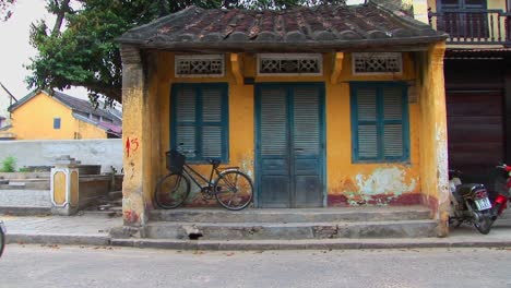 people and vehicles move by a small building in rural vietnam