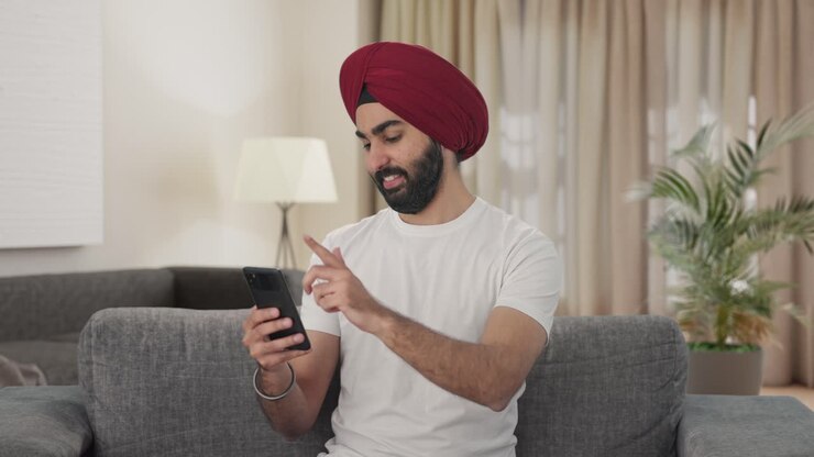 hombre indio sikh feliz usando teléfono móvil
