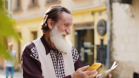hombre anciano feliz contando dinero dólar en efectivo, use la aplicación de calculadora de teléfono inteligente en la calle de la ciudad urbana