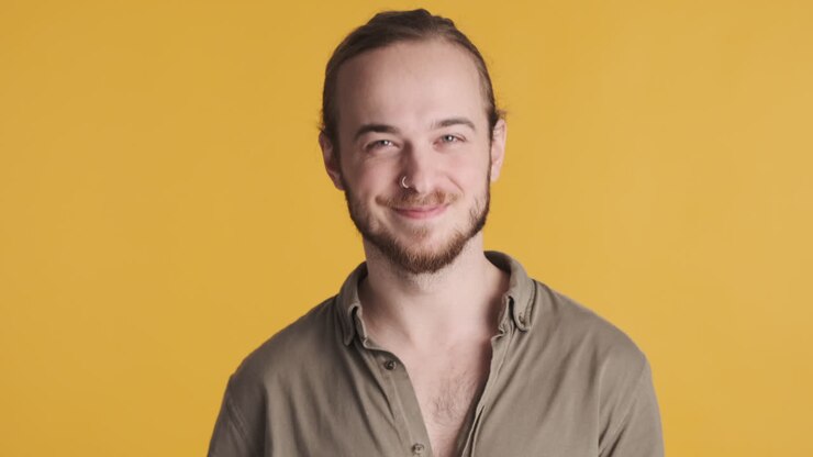 Giovane uomo caucasico che saluta con la mano la telecamera.