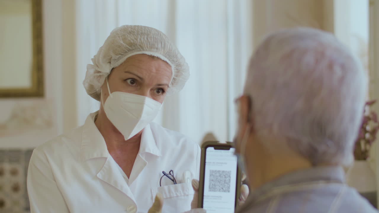 Врач показывает мужчине QR-код на экране телефона после вакцинации.