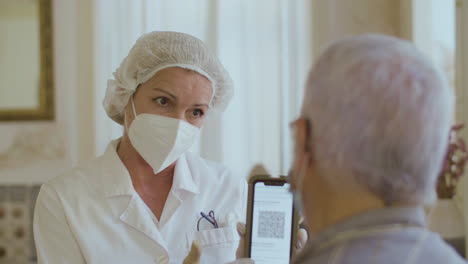 el médico muestra al hombre el código qr en la pantalla del teléfono después de la vacunación