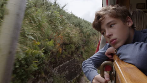 teenager looking out the window of a train