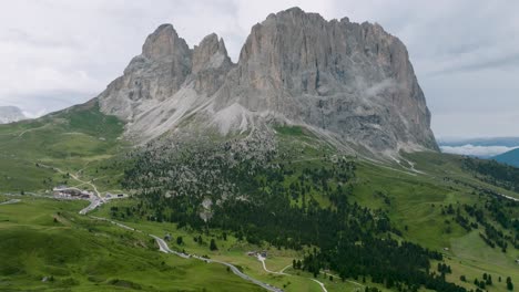 drone footage shows one of the huge high rocky mountains rising from the alpine meadows in the dolomites mountain range