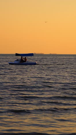 catamaran on sea background at sunset. men sailing in a blue catamaran on sea in the evening. vertical video