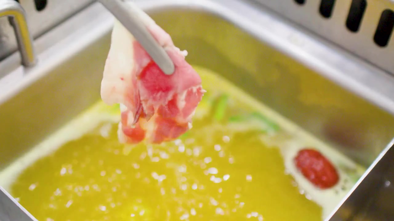 Primer plano de carne sumergiéndose en caldo hirviendo de olla caliente