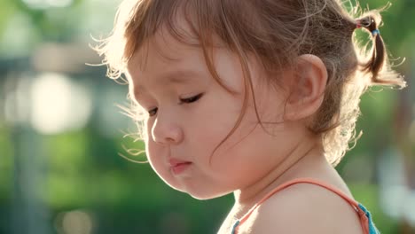 profile view of cute little girl biting snack but doesn't like taste - face close up slow motion