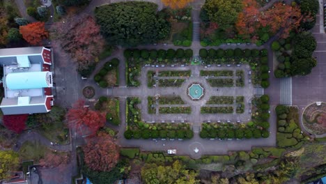 a formal garden with symmetrical layouts at dusk, aerial view