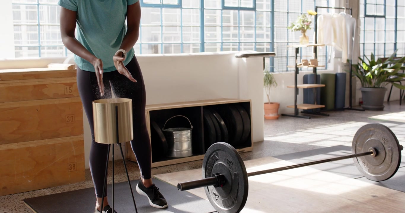 African American women in sportswear preparing lift in gym, grabbing chalk and coaching for barbell