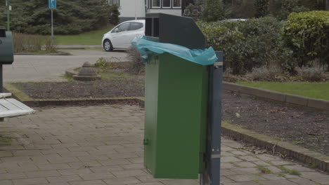 plastic garbagebag in green trashcan flapping in the wind