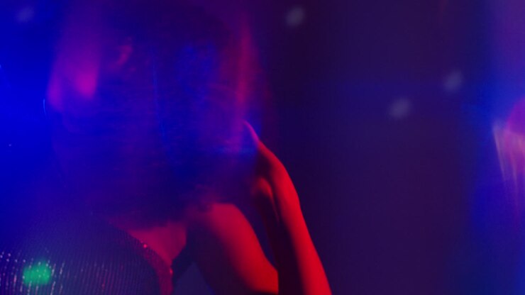 Primo piano di una giovane donna in un locale notturno, bar o discoteca che balla con luci scintillanti 5