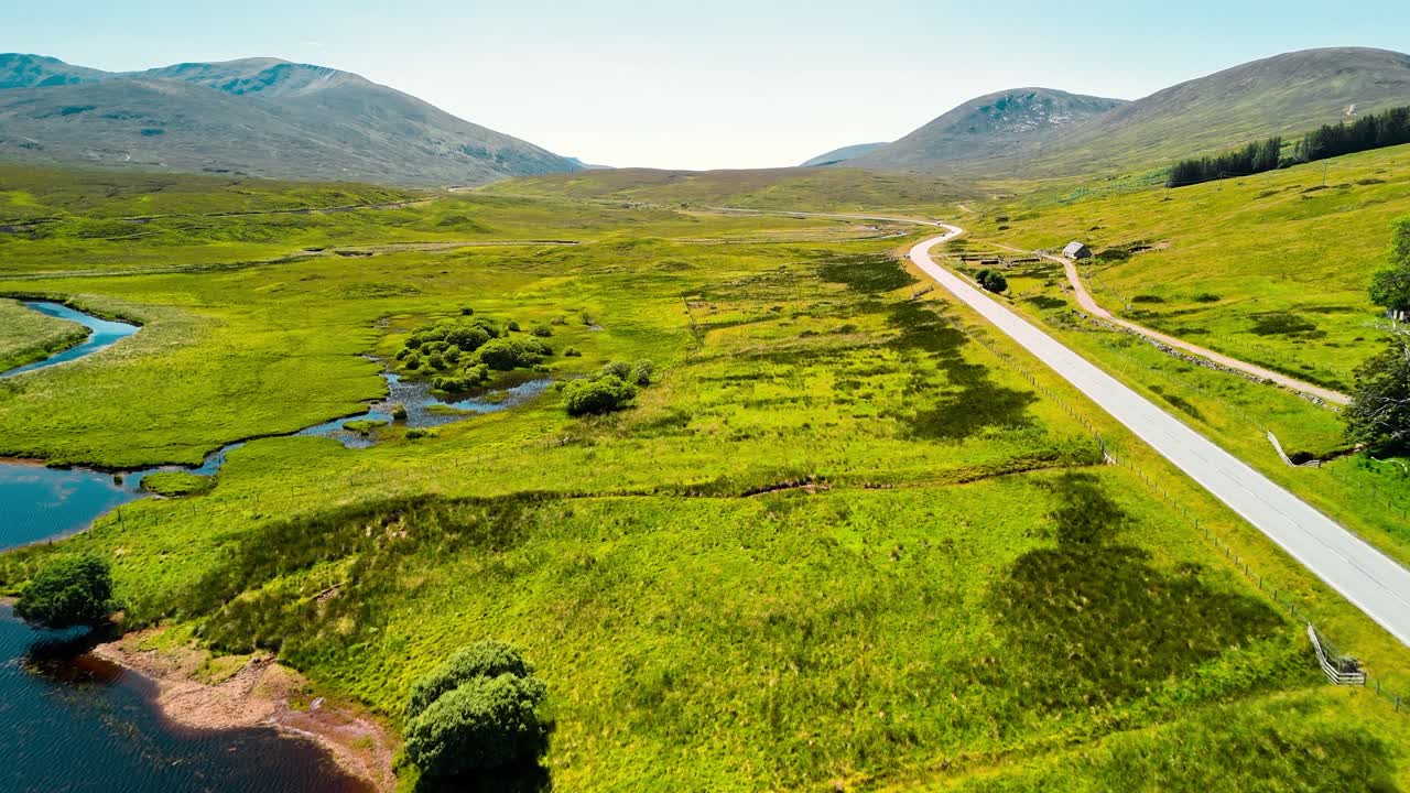 Scenic aerial view of a winding road through a green valley with mountains