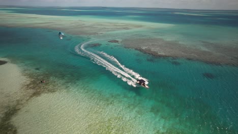 A-boat-approaching-a-sandy-key-with-turquoise-waters,-drone-shot,-sunny-day,-aerial-view