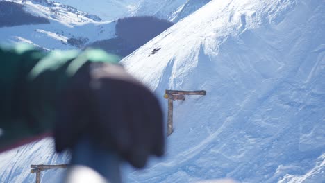 close-up varying focus between the gloves of a skier on a chairlift and the snowy ski run