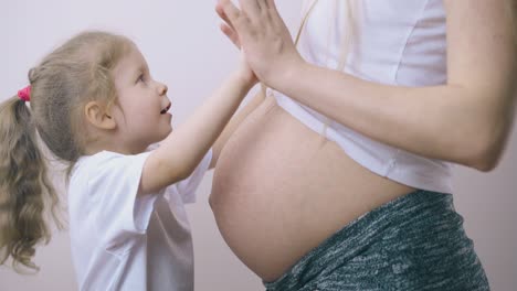 little girl has fan with young pregnant mommy at home