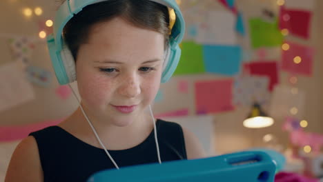 cute little girl using tablet computer listening to music wearing headphones enjoying online entertainment child having fun with portable touchscreen device at home