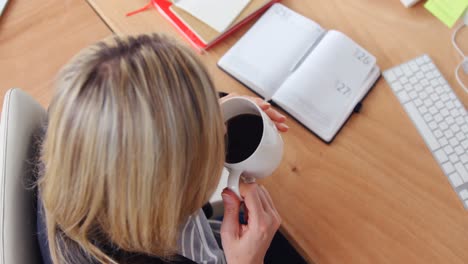 Businesswoman-having-coffee-at-her-desk