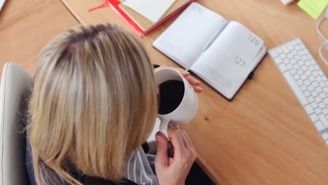 mujer de negocios tomando café en su escritorio