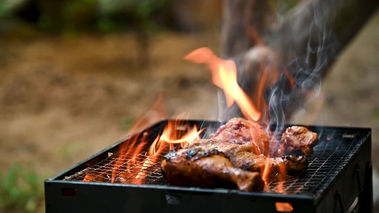 Slow-motion shot of masala poured over chicken drumsticks on a flaming BBQ grill in a backyard. The sizzling fire and spices create a mouthwatering cooking scene for food, lifestyle, and health